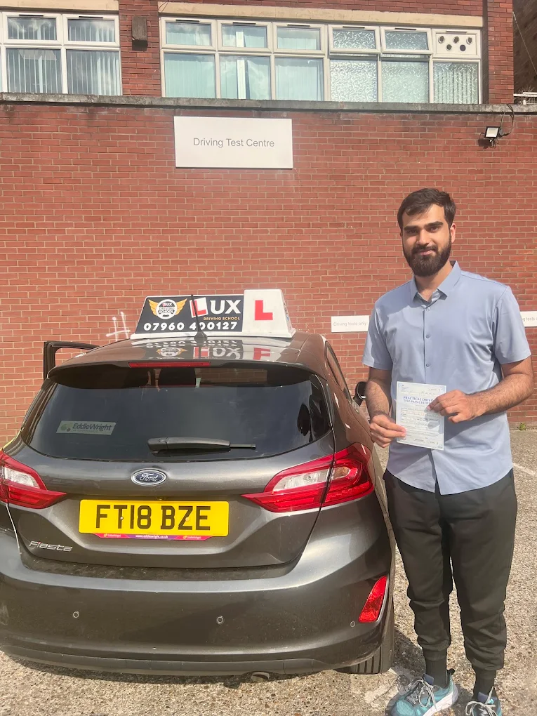 Successful driving student smiling with instructor after passing driving test in East London